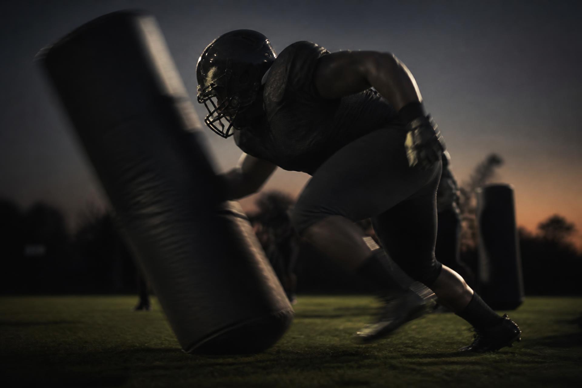 Defensive lineman exploding off the line past a blocking bag on a Texas grass field